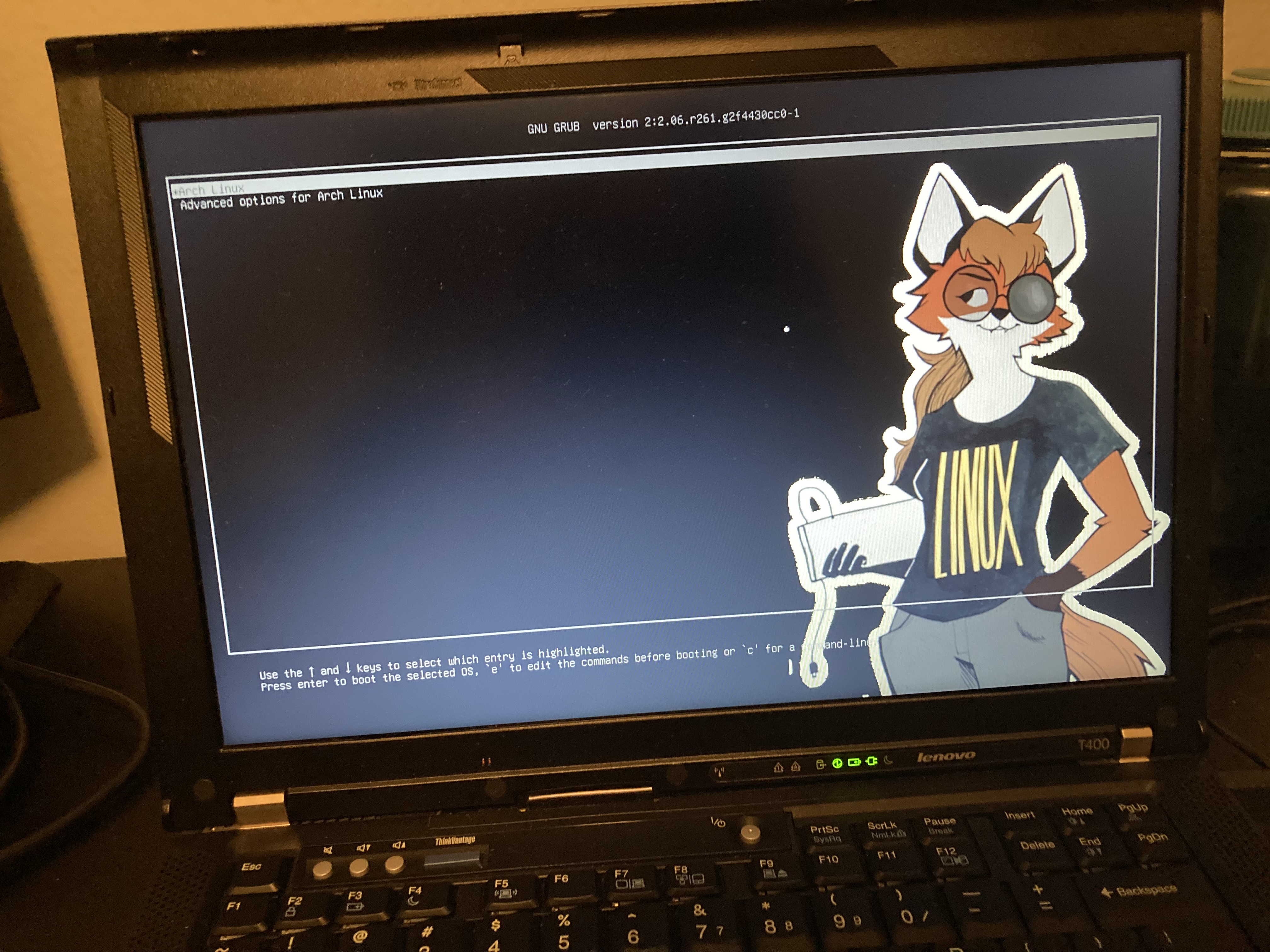 a thinkpad t400 displaying gnu grub with xenia, a foxgirl in a shirt that says LINUX on it, displayed as a splash screen